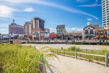 Beach entrance from in proximity to the Atlantic City Boardwalk with Boardwalk shops and hotel towers in distance.