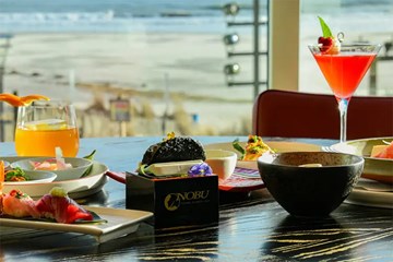 Nobu Atlantic City Table Setting with assortment of dishes and cocktails with an ocean view.