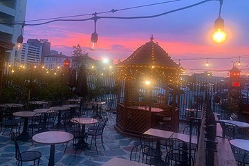 Irish Pub and Inn outdoor patio seating with lighting and small gazebo, and pinkish hue sunset visible.